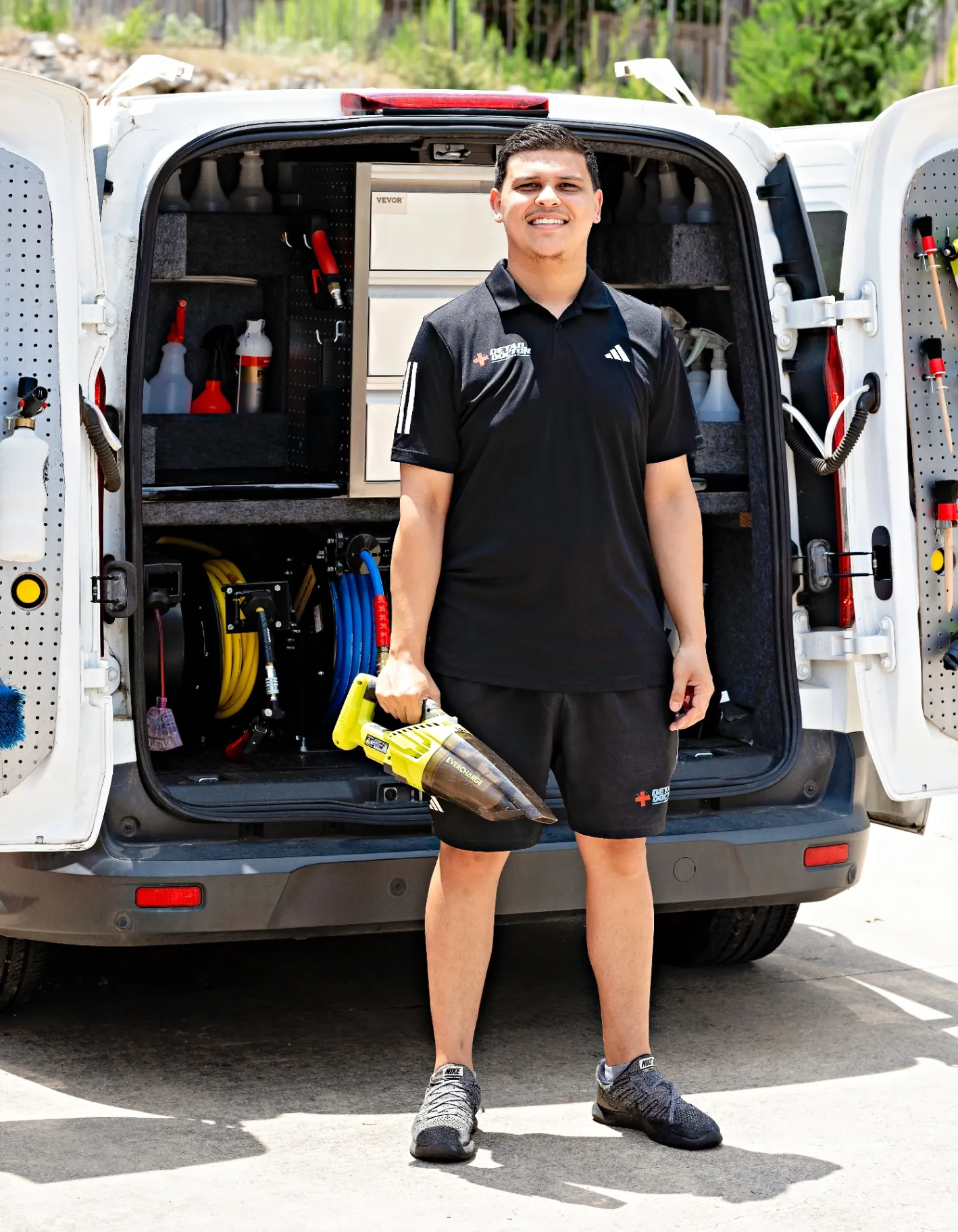 Eric standing in front of the Detail Doctor mobile van with rear doors open showing organized tools and equipment